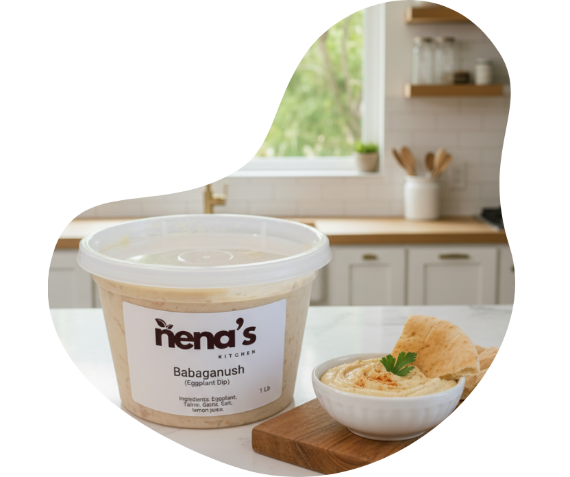 Nena’s Kitchen Babaganush organic eggplant dip in a container beside a bowl served with pita bread, displayed on a bright kitchen counter.